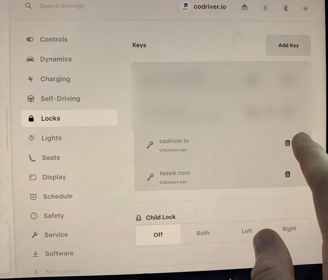 L’écran Verrouillage d’une Tesla : la liste des clés affiche codriver.io avec une icône de corbeille, et un doigt s’apprête à la toucher